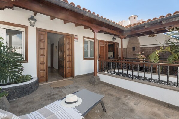 A patio with a lounge chair, a hat, and a stone planter.