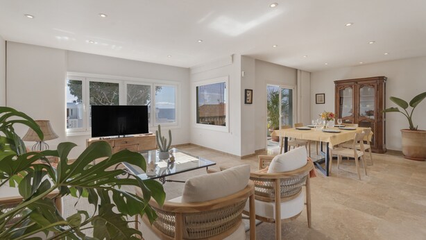 A spacious living room with a flat-screen TV, a dining area with a table and chairs, and a large potted plant. - Vacation Villa 'Spinnaker Playa' with Sea View, Private Terrace and Wi-Fi (Santiago del Teide)