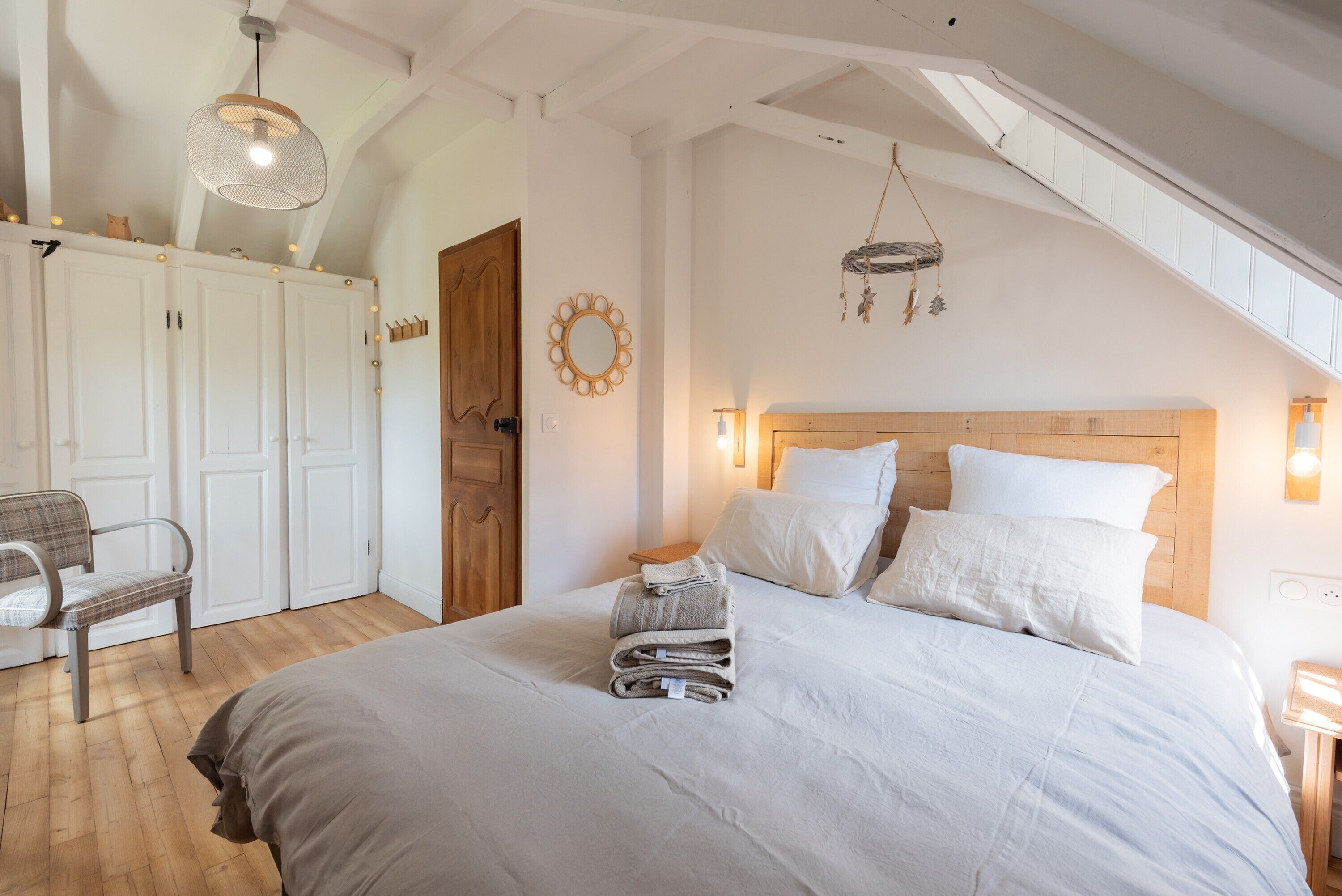 Une chambre à coucher comprenant un lit, une chaise, une armoire et un luminaire suspendu.