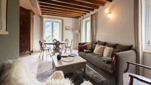 Una sala de estar acogedora con techo de madera, un sofá, una mesa de centro y un comedor con sillas y una mesa.
