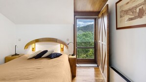 A bedroom with a bed, bedside lamps, a nightstand, a window with a view of greenery, and a framed picture on the wall. - Holiday Home 'Quinta Das Cavadas' with Mountain View, Private Pool and Wi-Fi (Canedo)
