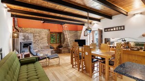 A cozy living area with a fireplace, wooden furniture, and a stone wall. - Holiday Home 'Quinta Das Cavadas' with Mountain View, Private Pool and Wi-Fi (Canedo)
