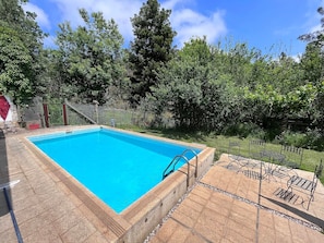 Ein rechteckiger Swimmingpool mit einer klaren, blauen Wasserfläche, umgeben von einer Stegterrasse.