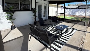 An outdoor patio with a ceiling fan, a table with chairs, and potted plants. - ‘The Gallery’ Spacious & Modern 4 Bedroom Getaway with Pool (Tampa)