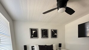 A modern bedroom with a bed, bedside tables, a ceiling fan, and abstract wall art. - ‘The Gallery’ Spacious & Modern 4 Bedroom Getaway with Pool (Tampa)