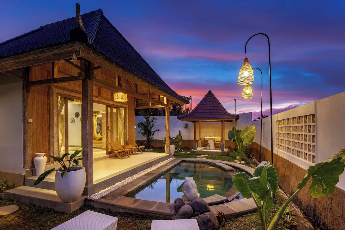 A traditional wooden building with a tiled roof, a small pool, and a gazebo.