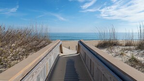 A concrete boardwalk leading to a beach with a clear view of the ocean. - Pinstripe Paradise-Kitty Hawk MP 5, Ocean View, 10 Yds to Beach, Pool, Hot Tub, Pets OK, Flex Stays (Kitty Hawk)