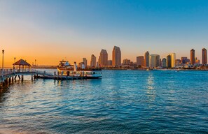 A waterfront cityscape with a pier, a boat, and a city skyline.