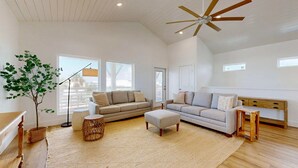 A spacious living room with two sofas, a coffee table, a floor lamp, and a ceiling fan. - Pet Friendly Beach Home, Shared Pool, Boardwalk to the Beach, Golf Cart Included (Port Aransas)