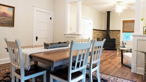 A dining area with a wooden table and light blue chairs, a fireplace, and a stone wall in the background. - Anderson Cottage: comfy 3 bedroom near stadium, winery, airport, & golf course! (Manhattan)