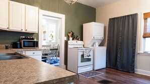 A kitchen with white cabinets, a microwave, a stove, and a refrigerator. - Anderson Cottage: comfy 3 bedroom near stadium, winery, airport, & golf course! (Manhattan)