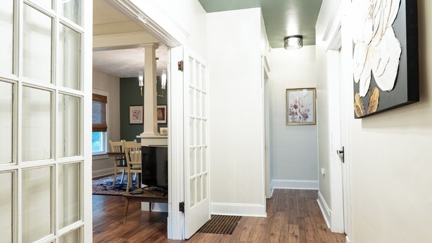 A hallway with wooden flooring, white walls, and a door leading to another room. - Anderson Cottage: comfy 3 bedroom near stadium, winery, airport, & golf course! (Manhattan)