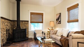 A cozy living room with a stone fireplace, a sofa, a coffee table, and a lamp. - Anderson Cottage: comfy 3 bedroom near stadium, winery, airport, & golf course! (Manhattan)