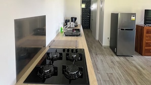 A modern kitchen with a gas stove, stainless steel appliances, and a wooden countertop. - Painapo - Mirimiri Lodge (Tumaraa)