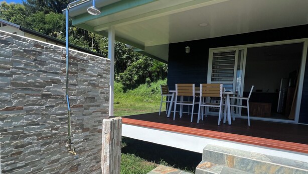 A covered outdoor area with stone steps leading to a seating area with chairs and a table. - Painapo - Mirimiri Lodge (Tumaraa)