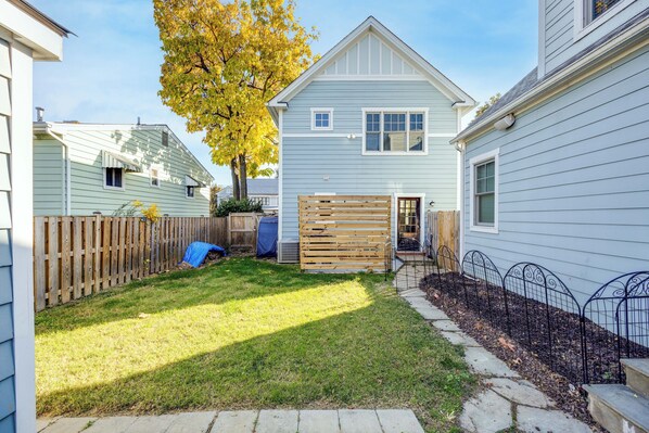A residential backyard with a wooden fence, a tree with yellow leaves, and a house with light blue siding. - Executive 4bdr House minutes from D.C (Arlington)