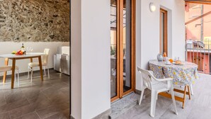 Un comedor con pared de piedra, una mesa con sillas y un balcón con mesa y sillas.