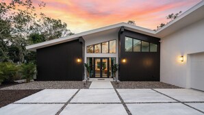 Een modern huis met twee verdiepingen, een ruime veranda, een garage en een oprit naar de ingang.