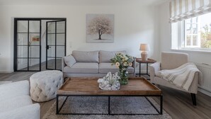 A modern living room with a grey sofa, a wooden coffee table, and a white armchair. - Baileys Hüs - Lovingly renovated "Baileys Hüs" in the picturesque village of Keitum on (Keitum)