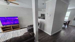 Una sala moderna con un televisor de pantalla plana, un sofá marrón oscuro y un mueble de entretenimiento de madera.