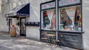Ein Café mit einem Schild mit der Aufschrift "LE CAFÉ GOURMET" und einer Speisekarte außen.