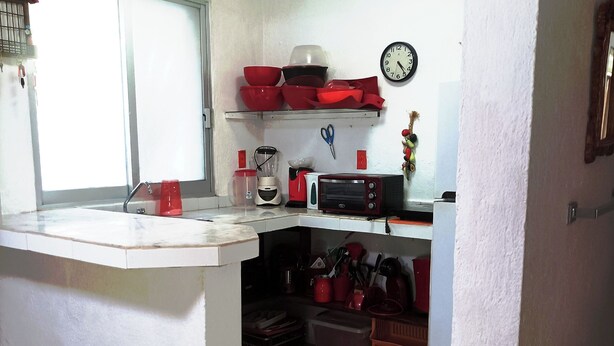 Une cuisine compacte avec un plan de travail blanc, un four à micro-ondes, un grille-pain et une horloge murale.