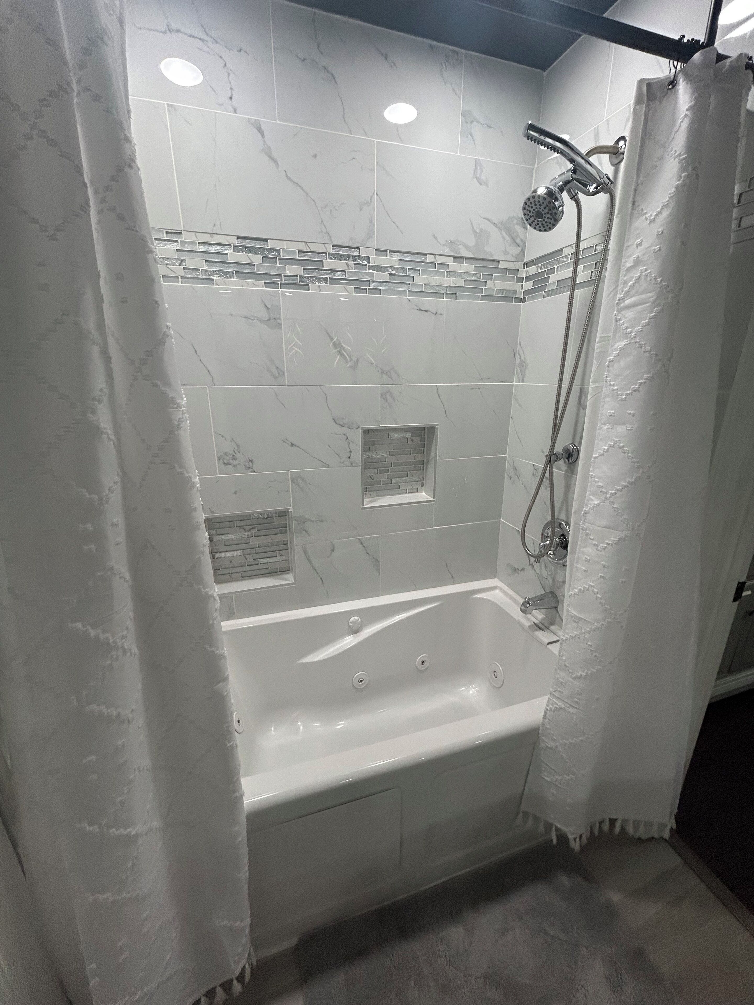 Un baño moderno con bañera, ducha y baldosas de mármol.