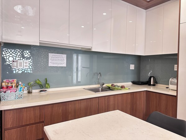 A modern kitchen with white cabinets, a marble countertop, and a built-in sink.