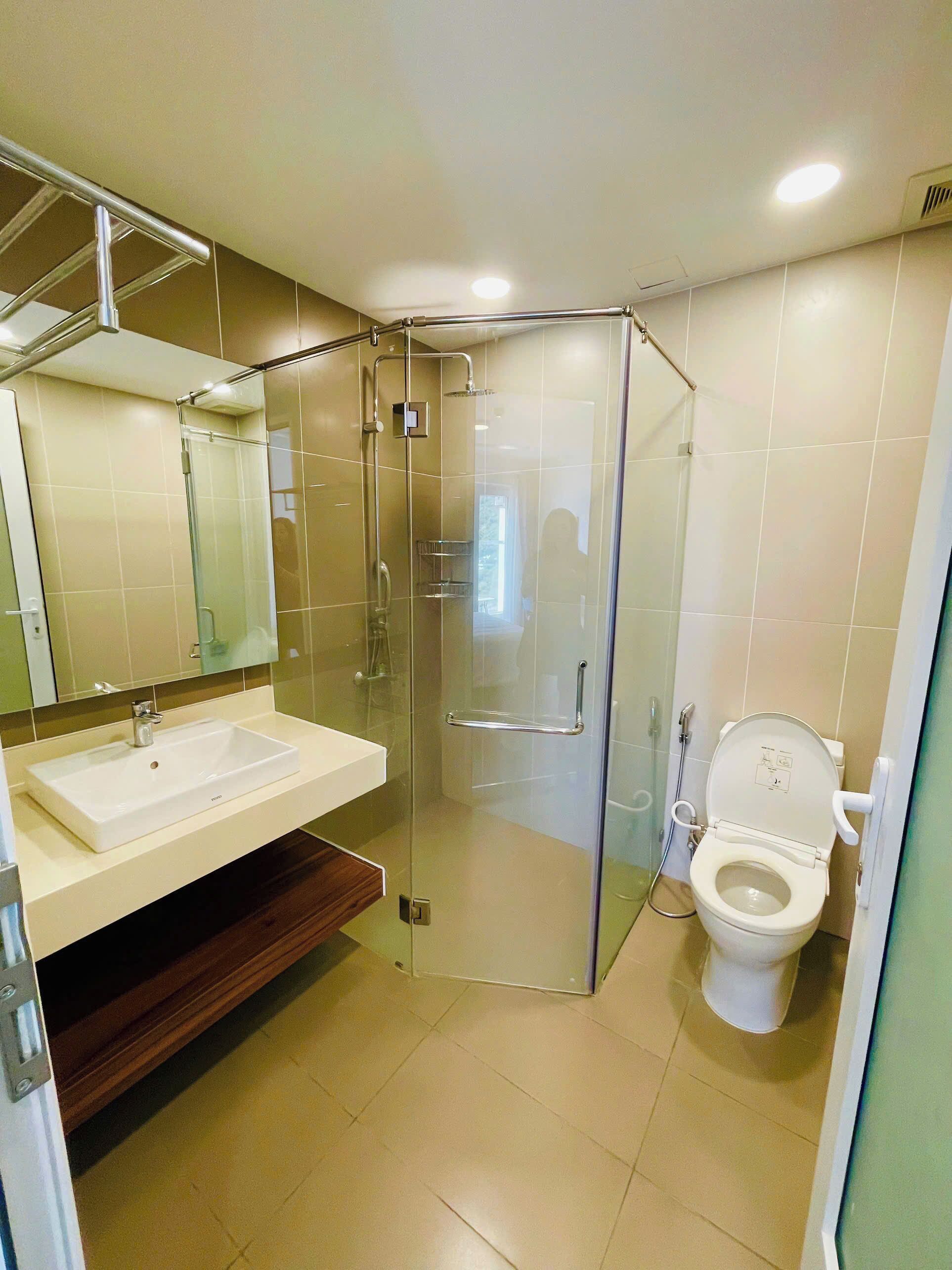 Une salle de bain moderne avec une douche à parois de verre, un lavabo blanc et des toilettes.