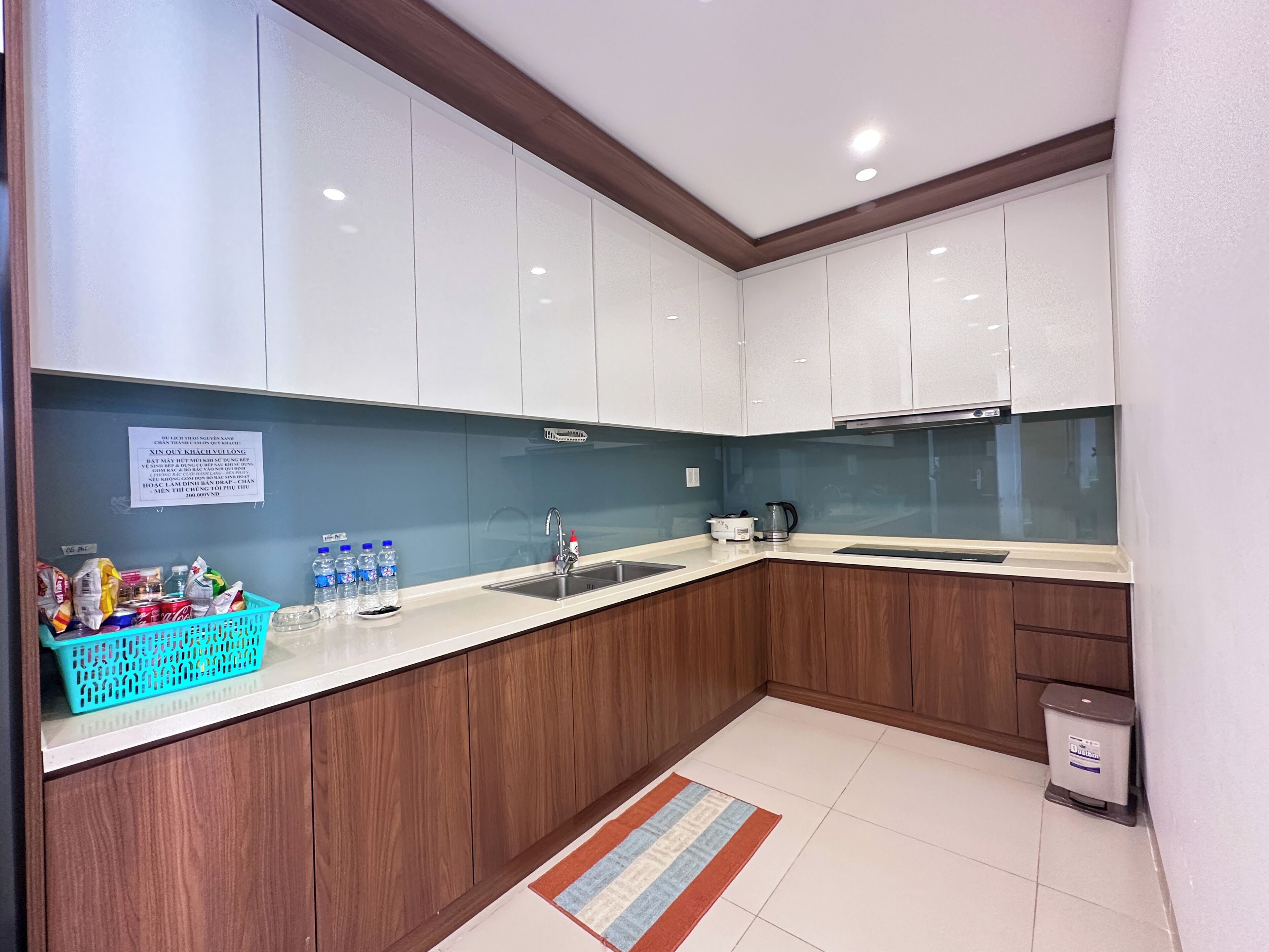 A modern kitchen with white cabinets, a wooden countertop, and a stainless steel sink.