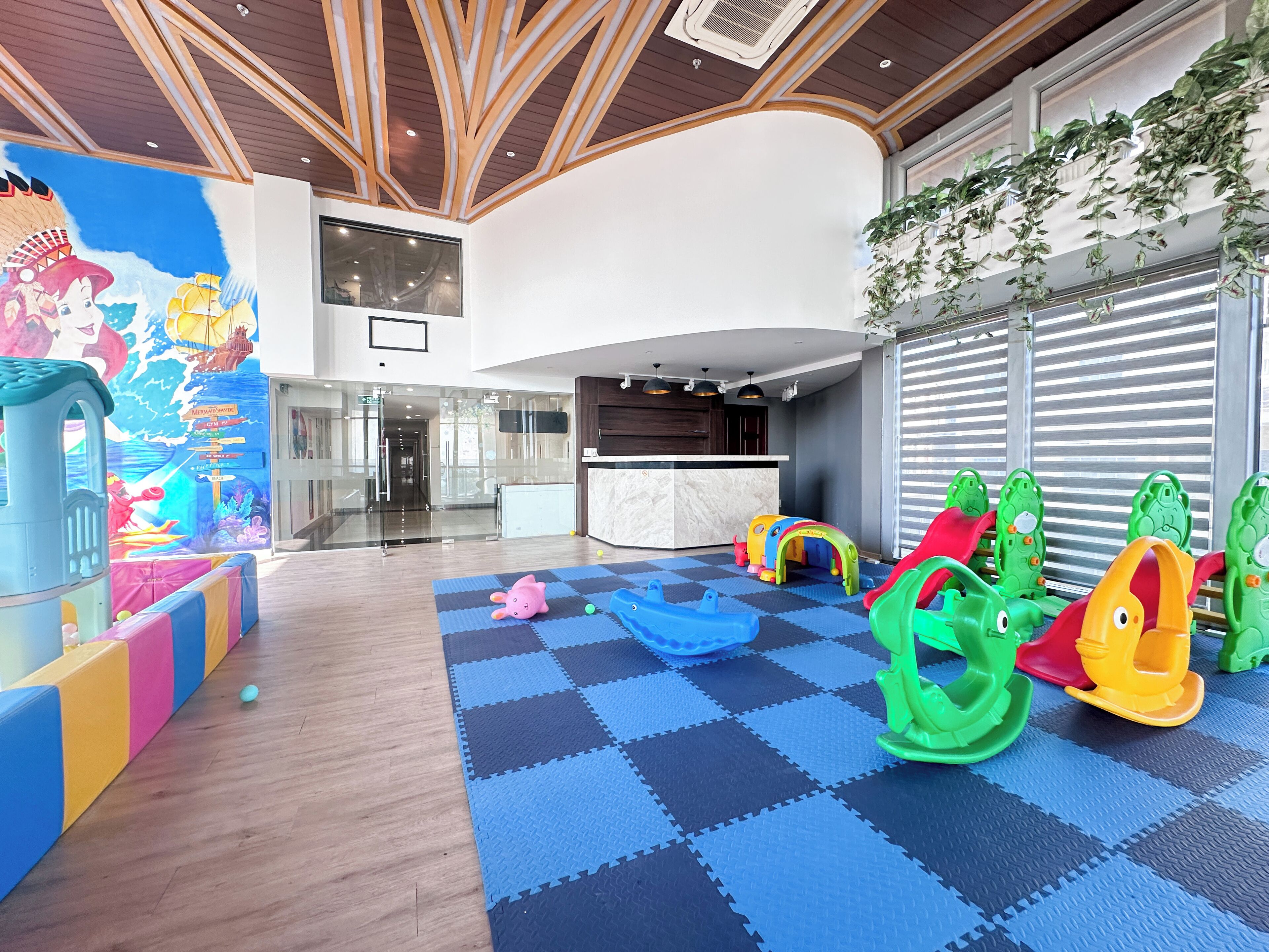 Zona de juegos infantiles con estructuras de juego coloridas y piso a cuadros.