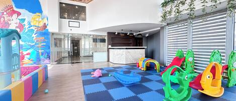 Zona de juegos infantiles con estructuras de juego coloridas y piso a cuadros.