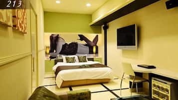 A modern hotel room with a bed, a TV, a desk, and a chair.