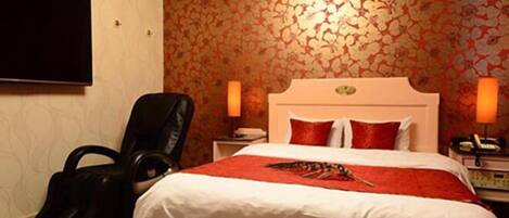 Een hotelkamer met een bed, een stoel, een bureau en een televisie.