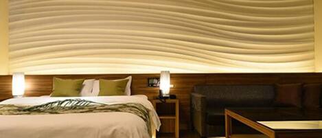 Ein Hotelzimmer mit einem Bett, einem Nachttisch aus Holz, einer Lampe, einem Sofa und einem Couchtisch.