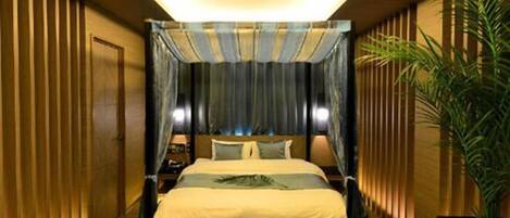 Una habitación de hotel moderna con una cama grande, una mesita de noche y una planta en maceta.