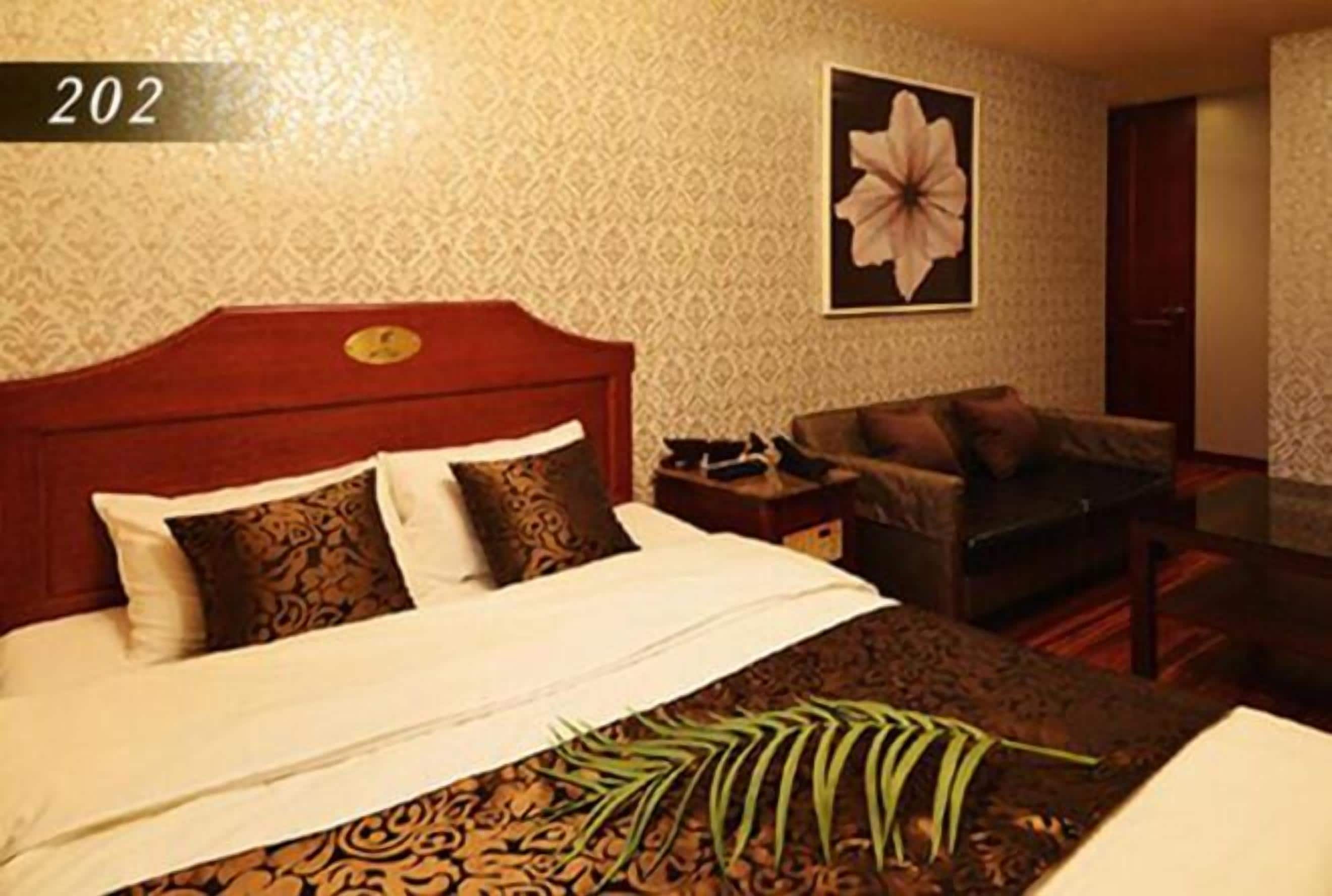 Een hotelkamer met een groot bed, een bank, een salontafel en een wand met een bloemschilderij.