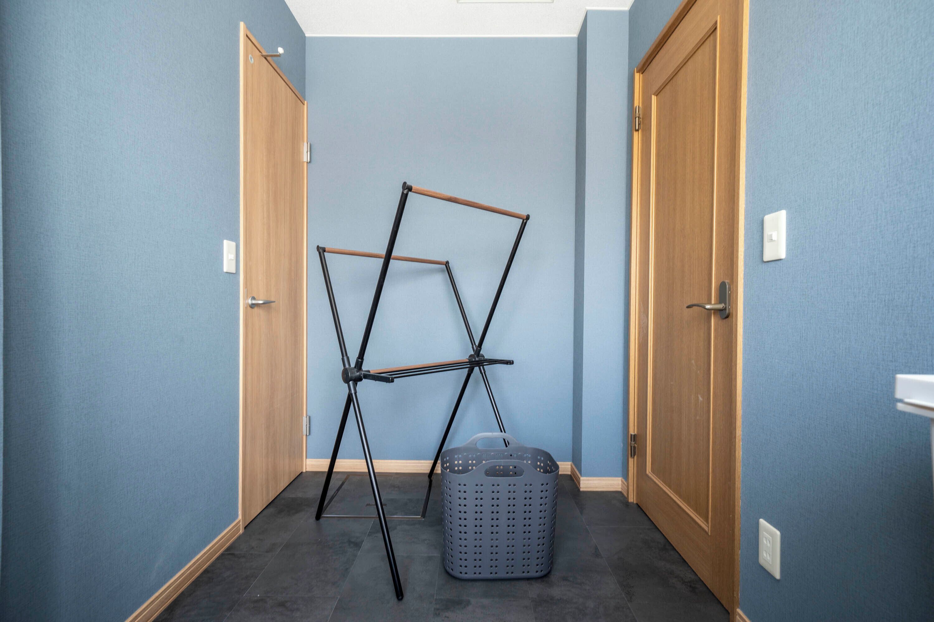 A hallway with blue walls, wooden doors, and a laundry basket.