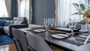 Zona de menjador moderna amb una taula fosca preparada per a dues persones, dues copes de vi i un ordinador portàtil.