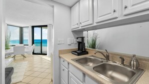 A modern kitchen with a double sink, white cabinets, and a coffee maker.