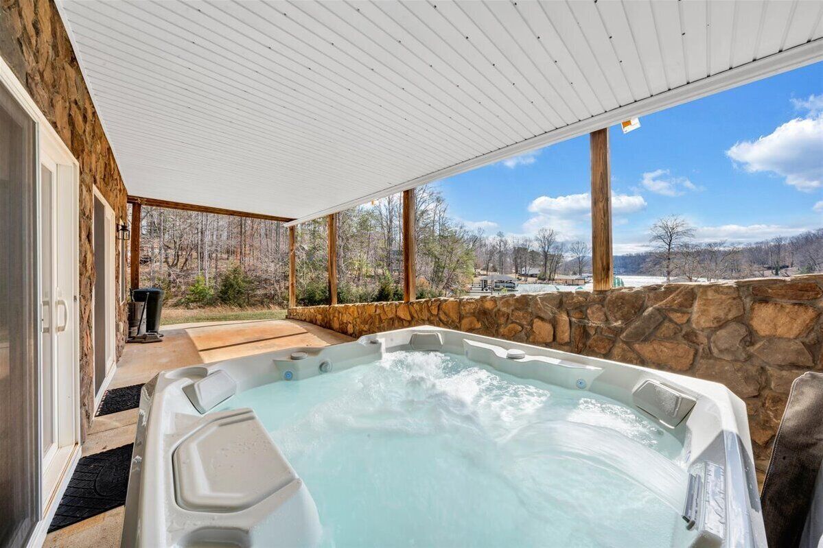 A hot tub in a covered outdoor area with stone walls and a view of a mountainous landscape.