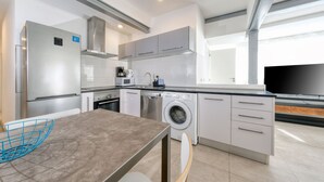 Een moderne keuken met roestvrijstalen apparatuur, een ingebouwde wasmachine en een flatscreen televisie.