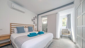 Een moderne hotelkamer met een groot bed, een houten hoofdbord, een klein nachtkastje en een stoel bij het raam.