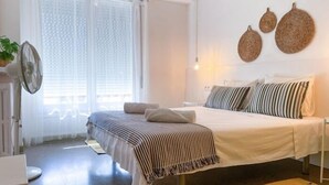 Un dormitorio con cama, mesita de noche y ventana con cortinas.