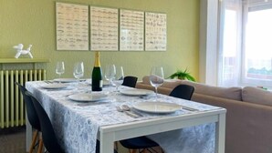 Un comedor con una mesa preparada para cuatro personas, una botella de champán e ilustraciones de peces en la pared.