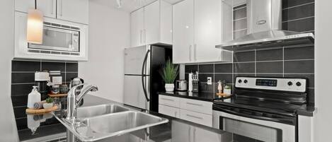 A modern kitchen with stainless steel appliances, a central island with a sink, and a microwave above the island.