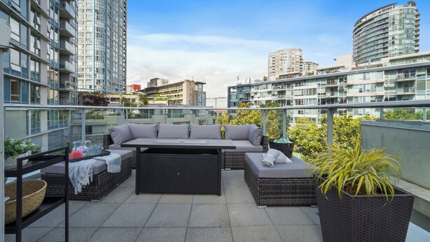 Une terrasse sur le toit dotée d’un espace salon extérieur moderne, comprenant un ensemble de canapés et une table à manger, le tout agrémenté de plantes en pot.