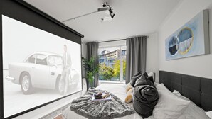 Une chambre avec une grande fenêtre, un lit recouvert d’une couverture moelleuse et un tableau accroché au mur.