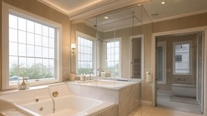 Une salle de bain spacieuse avec une grande baignoire, une douche séparée et un dressing fermé par des parois de verre.