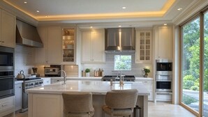 Une cuisine spacieuse dotée d’un grand îlot central, d’appareils électroménagers modernes et bénéficiant d’un éclairage naturel abondant grâce à de grandes fenêtres.